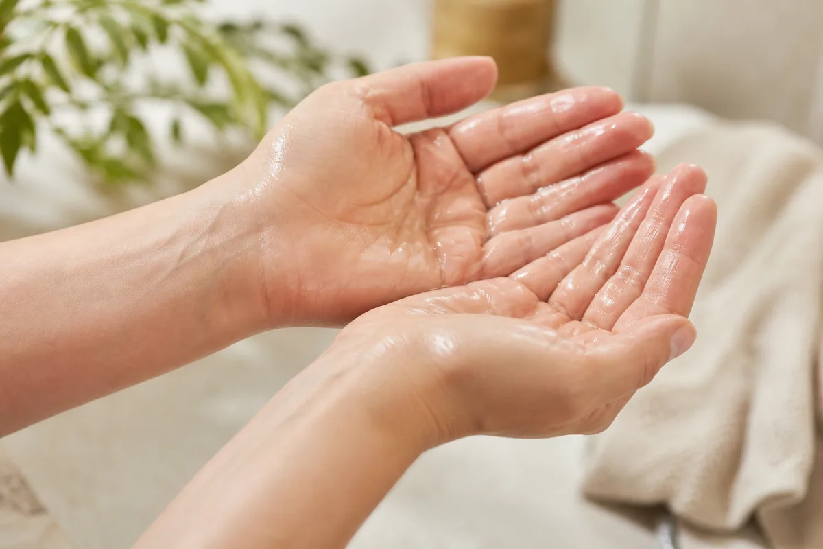 Mains réchauffant quelques gouttes d&rsquo;huile entre les paumes avant application sur le visage